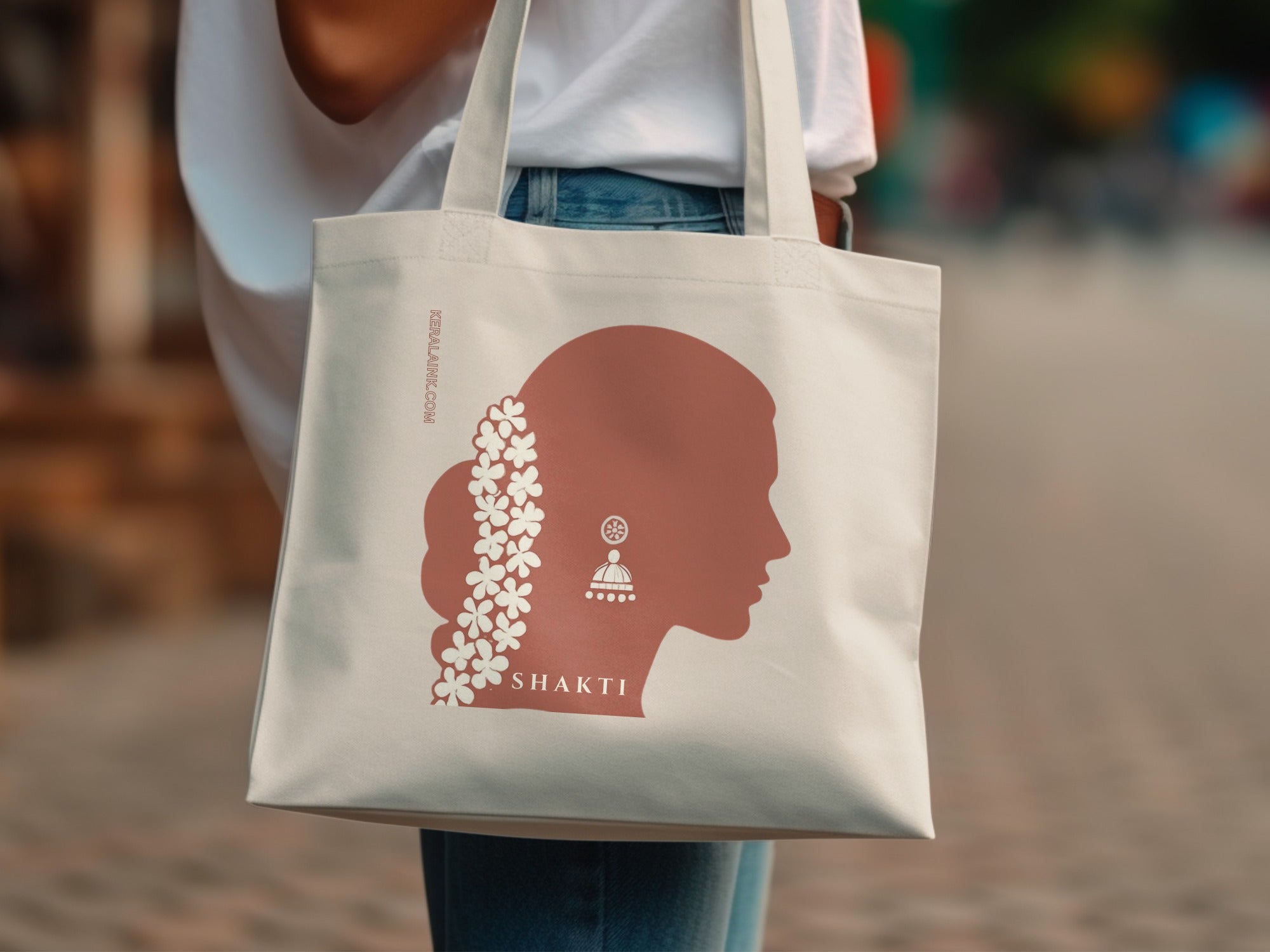 Cream tote bag with "SHAKTI" and silhouette of woman with floral hair ornament.